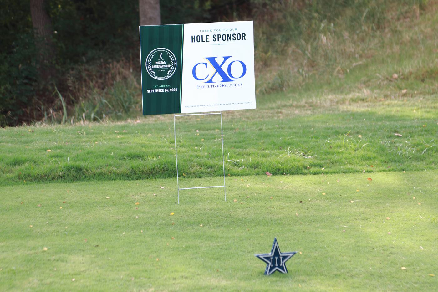 CXO Executive Solutions hole sponsor sign beside a Cowboys star tee marker