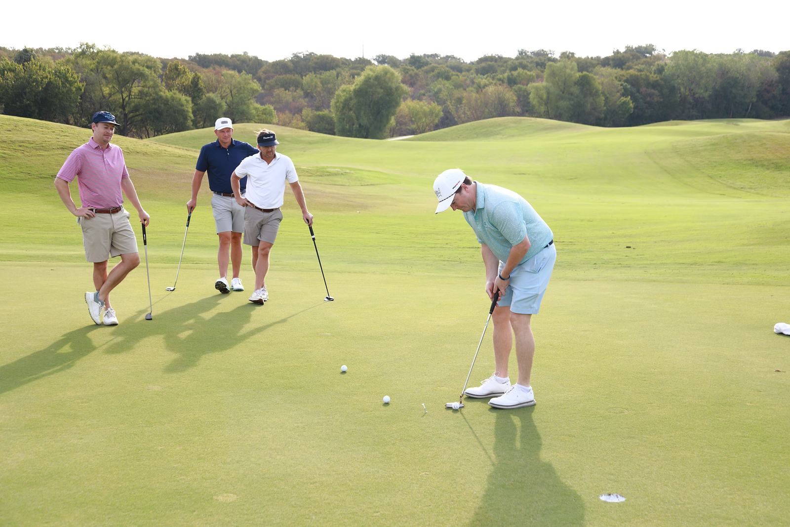 A player putting while three teammates look on