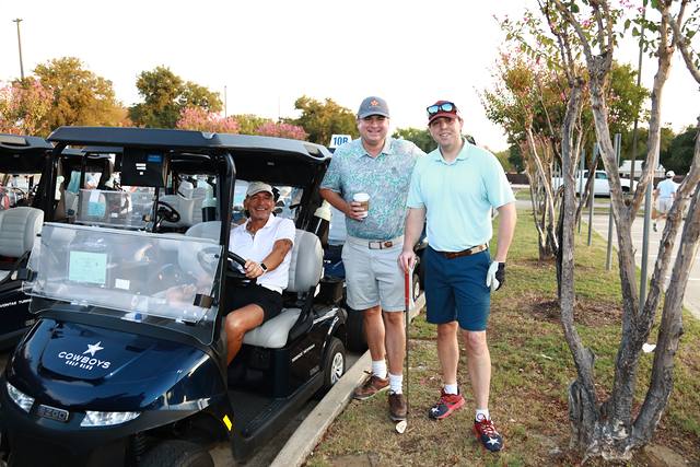 Three players posing beside their cart before the round