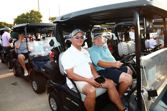 Two players smiling from their cart before the round