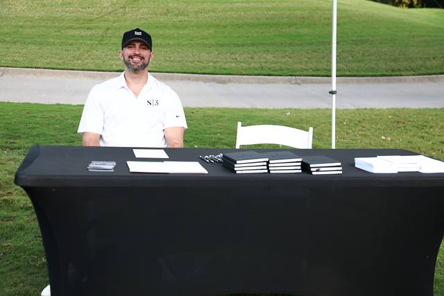 A sponsor from S3 smiling at his table on the course