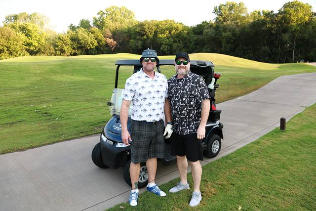 Two players posing beside their cart on the cart path