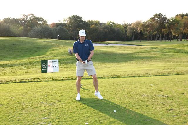 A player lining up his tee shot beside a hole sponsor sign