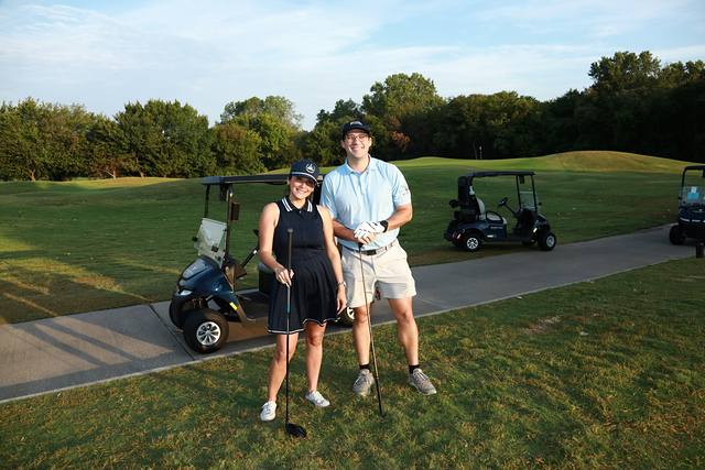 Two players posing by their cart on the cart path