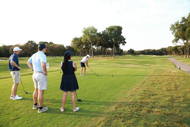 A group watching a teammate tee off