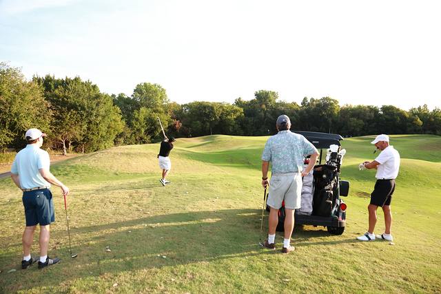 A player hitting while his group waits by the cart