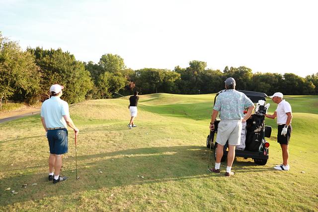 A group waiting by their cart as a teammate hits