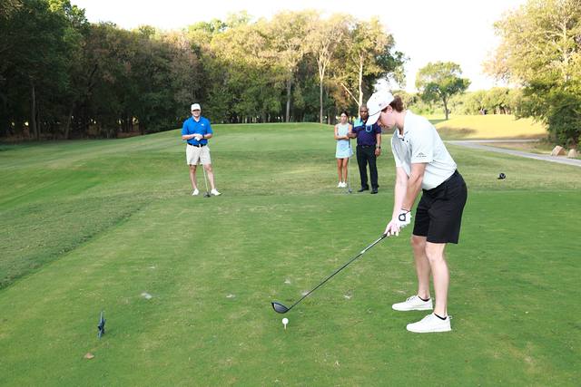 A player addressing his tee shot while his group watches