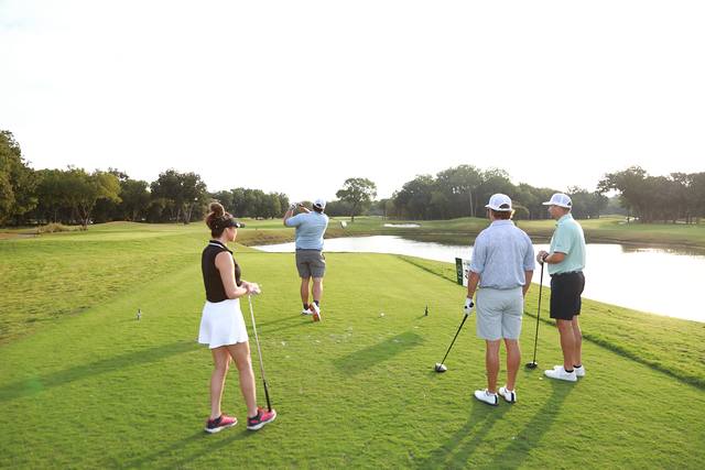 A player getting ready to tee off while her group waits beside a pond