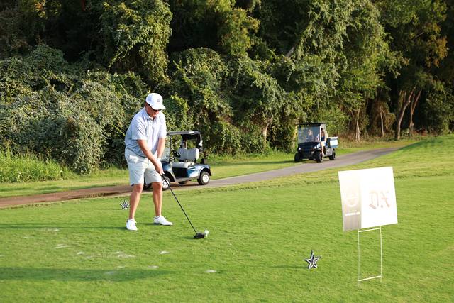 A player swinging beside The Dallas Express hole sponsor sign