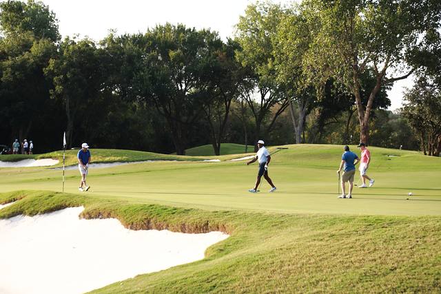 Players on a green beside a bunker at Cowboys Golf Club
