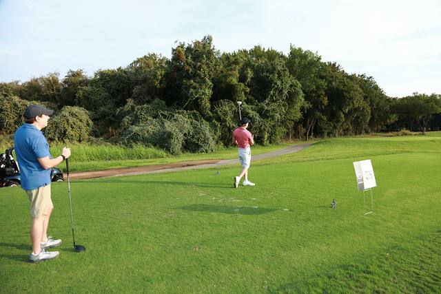 A player teeing off with his partners down the fairway