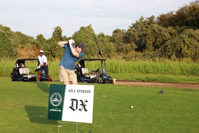 A player teeing off behind The Dallas Express hole sponsor sign