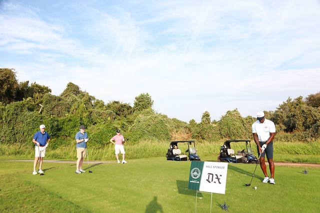 A group teeing off behind The Dallas Express hole sponsor sign