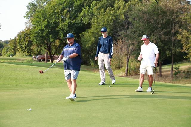 A player finishing his swing while his partners look on