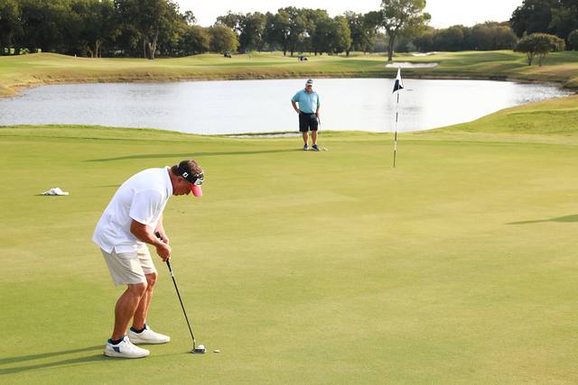 A player lining up a putt with a pond behind the green