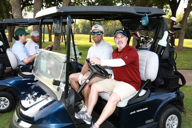 Two players smiling from their cart