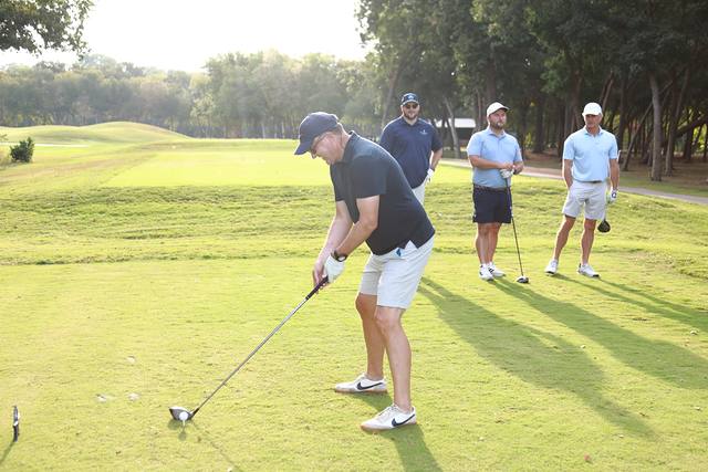 A player addressing his tee shot while his group watches