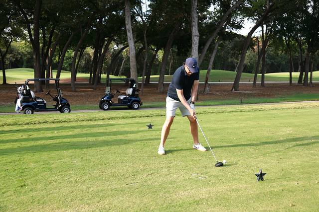 A player addressing his tee shot with carts behind him