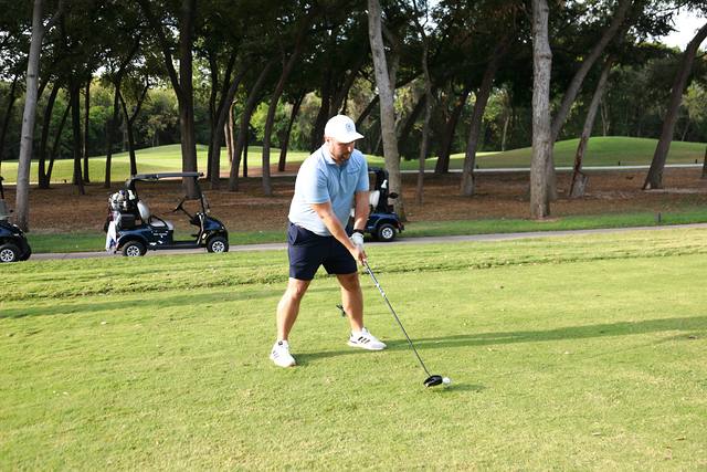 A player teeing off with carts lined up behind him