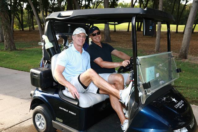 Two players posing in their cart on the cart path