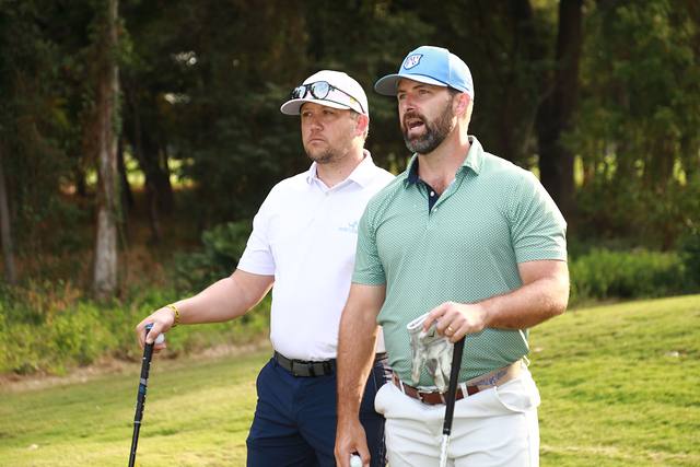 Two players watching a shot with clubs in hand