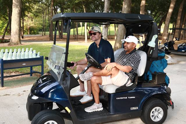 Two players relaxing in their cart beside a cooler of water