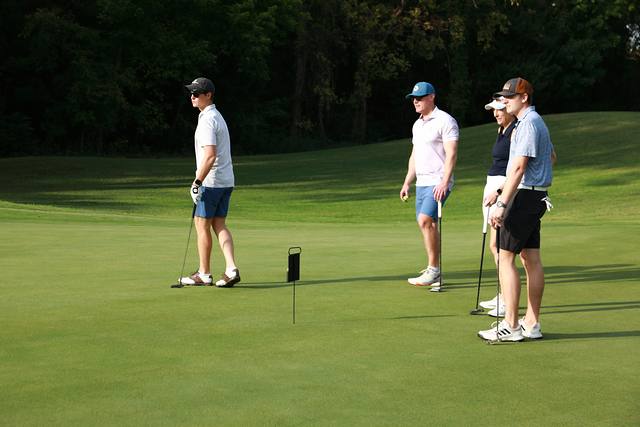 A group waiting on a green while a teammate lines up