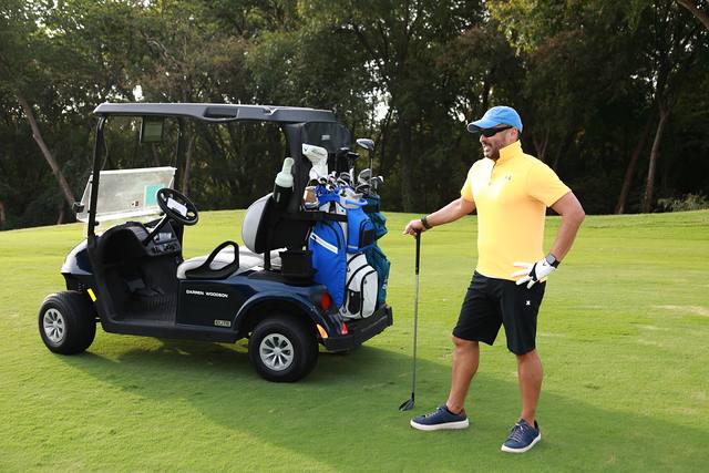 A player posing with his club beside his cart