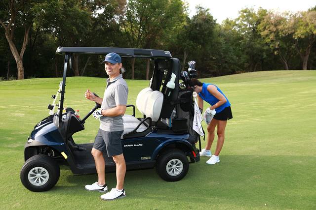 A player standing beside his cart on the fairway