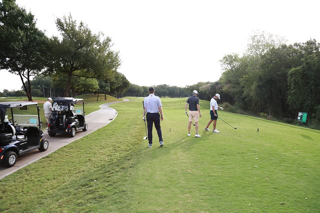 A group teeing off beside the cart path