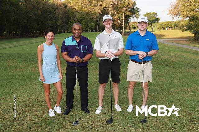 A group posing with their drivers on a tee box