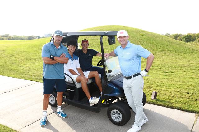 Three players posing beside their cart