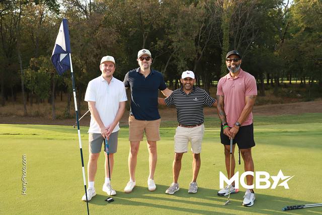 A group posing beside the flag on a green