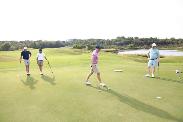 A group putting on a green with water in the distance