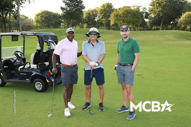 Three players posing beside their cart