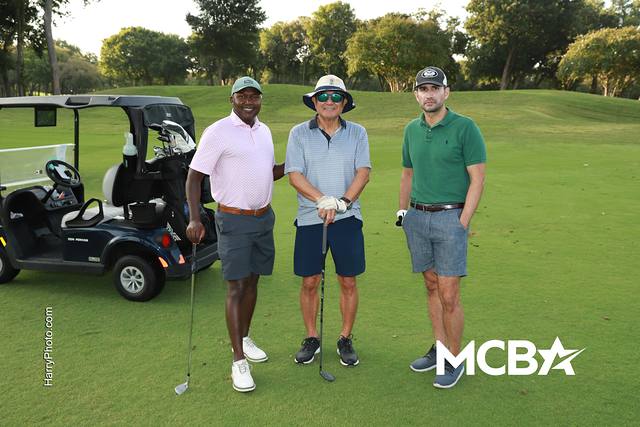 Three players smiling beside their cart