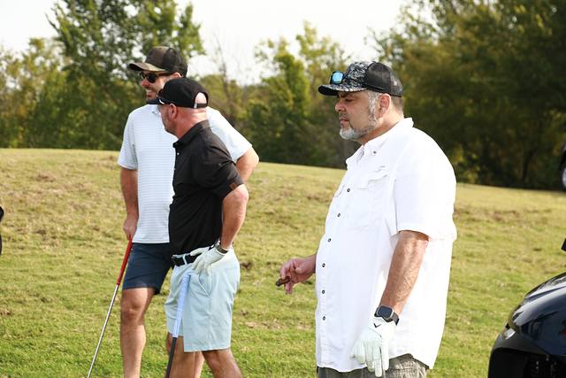 Three players talking beside their cart