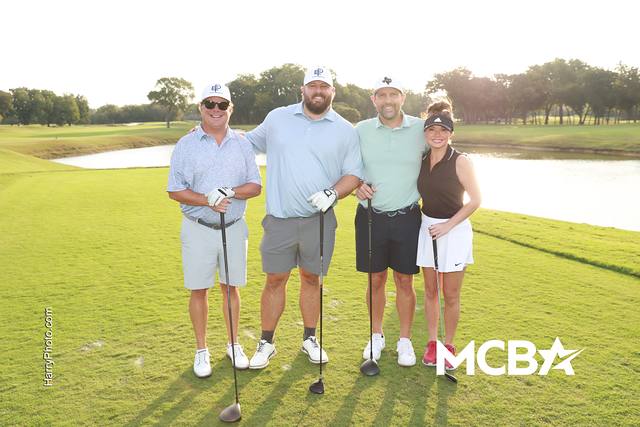 A group posing on the course with a pond behind them