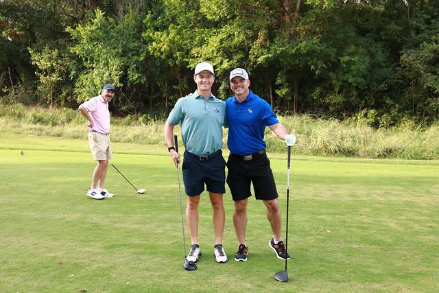 Two players posing on a tee box while a third gets ready to hit