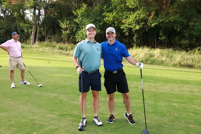 Two players posing on a tee box with their drivers