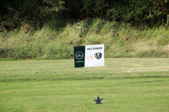 The Dallas Safari Club hole sponsor sign beside a Cowboys star tee marker