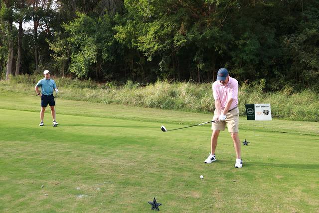 A player teeing off beside the Dallas Safari Club hole sponsor sign