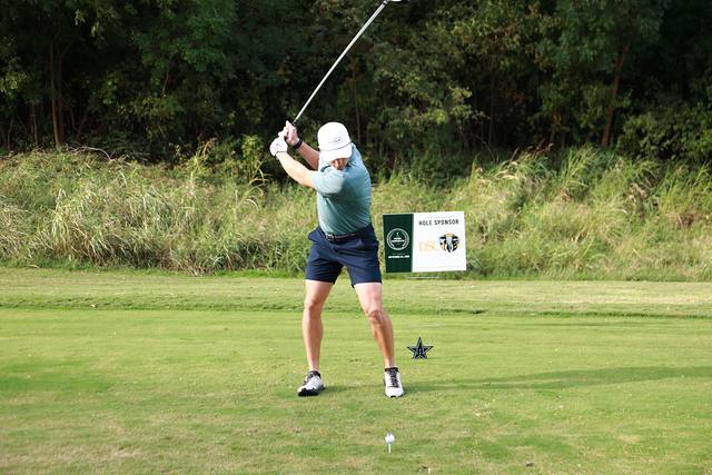 A player finishing his swing beside the Dallas Safari Club hole sponsor sign