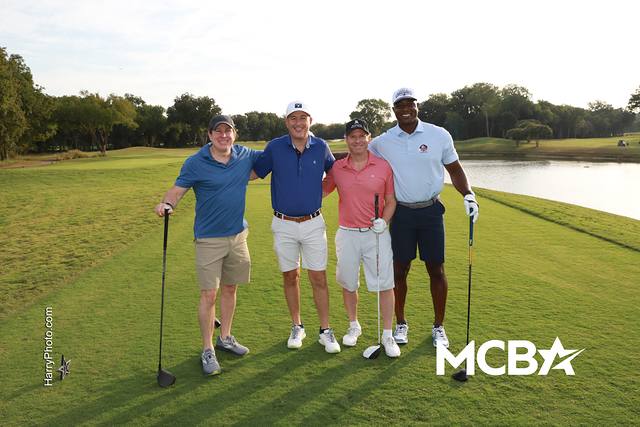 A group posing on a tee box beside the water