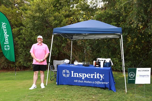 A player at Insperity's tent beside its hole sponsor sign