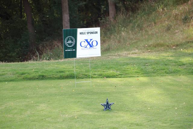 CXO Executive Solutions hole sponsor sign beside a Cowboys star tee marker