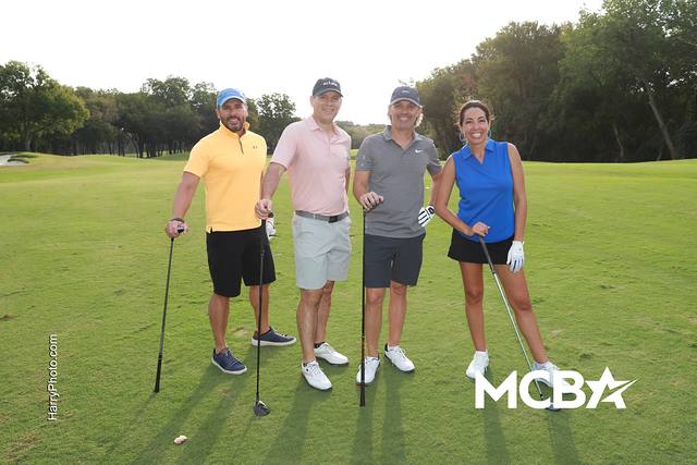 A group posing on a tee box with their clubs