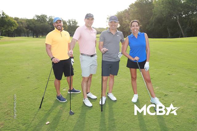 A group smiling on a tee box with their clubs