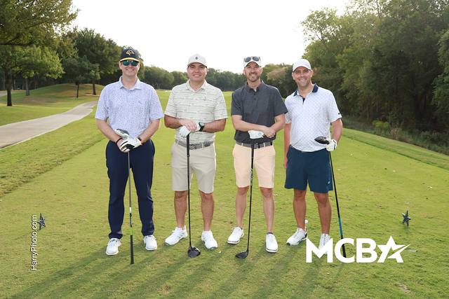 A group smiling with their drivers on a tee box